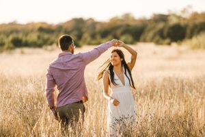 During their engagement session with Pamela Clark in Brushy Creek, a couple dances in a tall golden field
