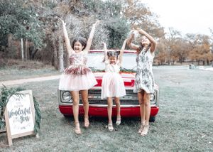 Three sisters toss fake snow in front of a 1970 Red Chevy C10 during a Christmas mini session with Pamela Clark in Texas