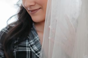 A bride smiles tenderly as she leans in close to her veil before dressing for her wedding