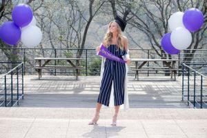 During her senior photo session with Pamela Clark, a girl wears a graduation cap and poses with a Graduate sign