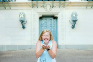 A University of Texas graduate blows confetti during her senior photo session with Pamela Clark at UT Austin