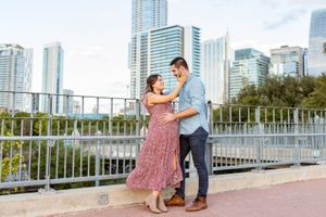 An expectant couple pose on the Lamar bridge with Austin Skyline behind them during a maternity shoot with Pamela Clark