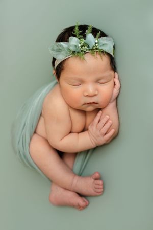 Baby girl wrapped in sage green and posed in side laying position by Cedar Park Newborn Photographer Pamela Clark