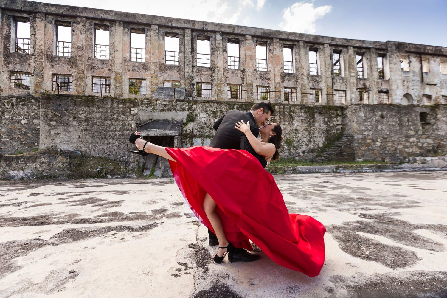 A dramatic dance pose with flowing red dress against ruins of an old building.
