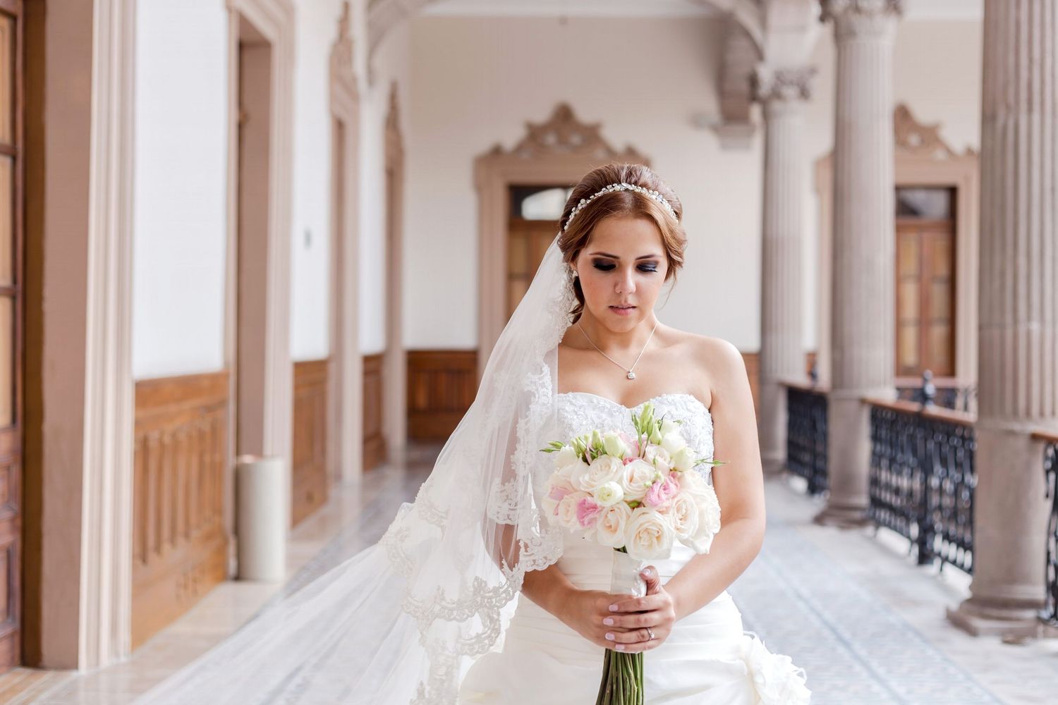 Beautiful bridal portrait in elegant corridor holding pink and white bouquet.