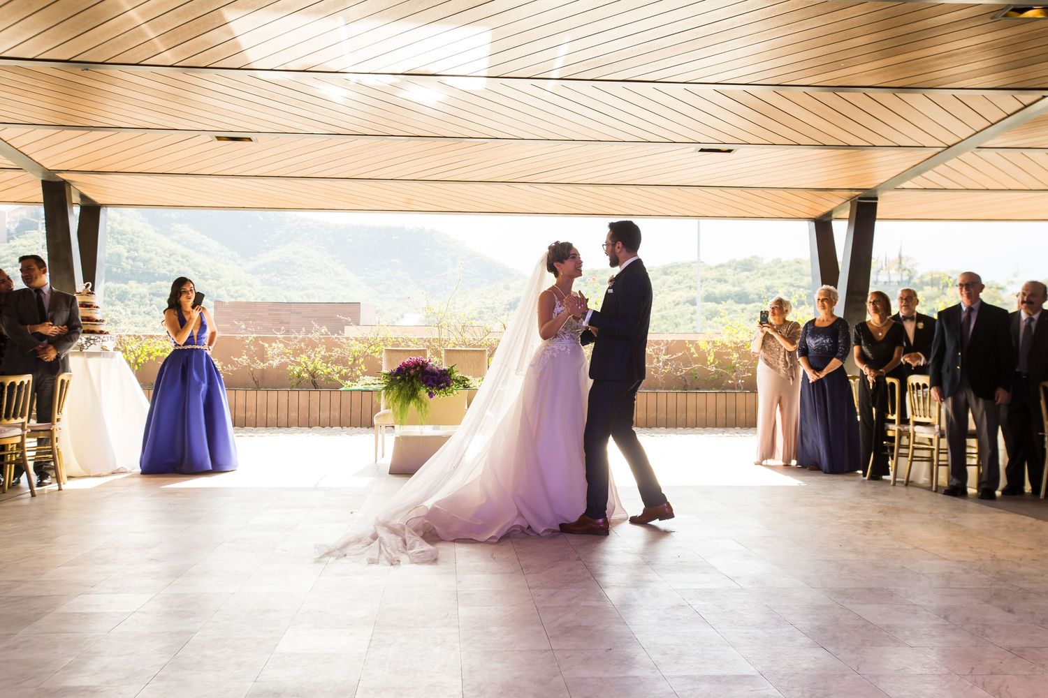 A wedding dance takes place in an elegant venue with mountain views through large windows.