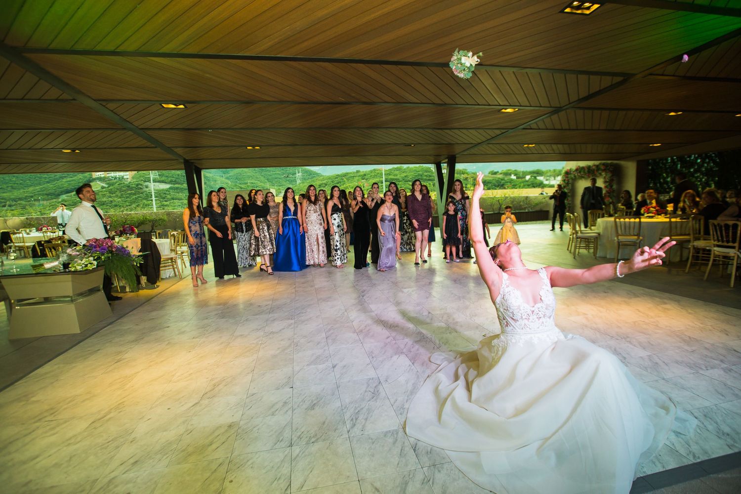 A wedding celebration in full swing with guests dancing on a beautifully lit dance floor.