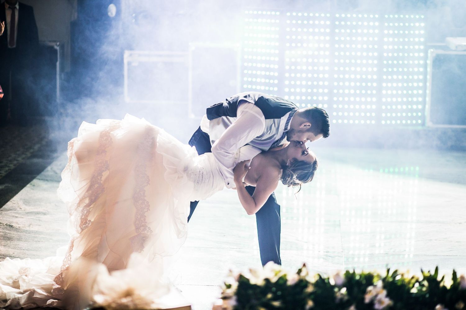 A romantic dance dip set against a moody backdrop with dramatic lighting and smoke effects.