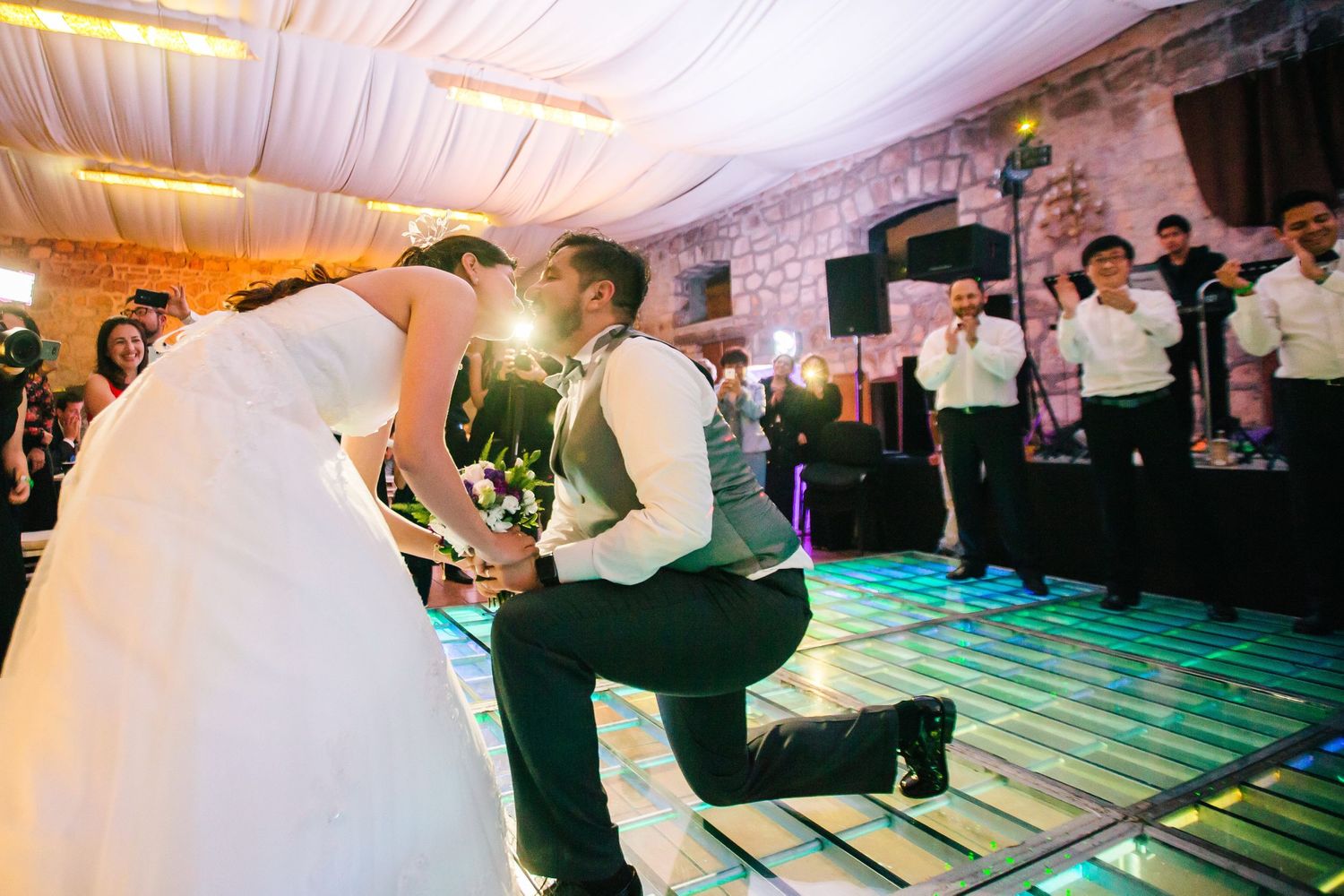 A romantic dance moment on an illuminated reception floor during a wedding celebration.