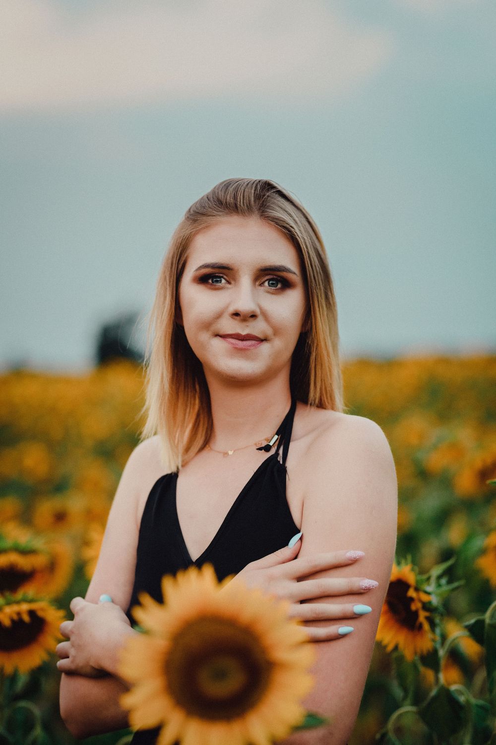 Portrait in sunflower field during golden hour with vibrant yellow blooms.