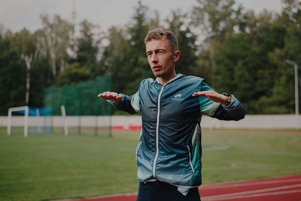 Athletic figure performing dynamic stretching movements outdoors on a sports field.