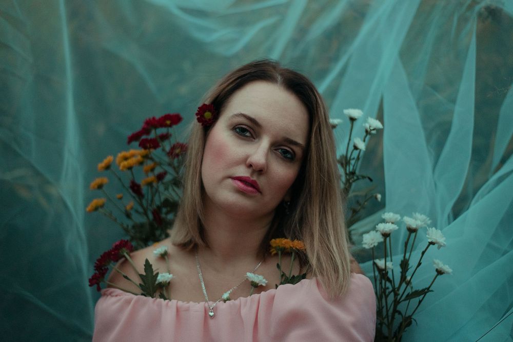 Artistic portrait in turquoise tones with delicate flowers and soft lighting creating a dreamy atmosphere.