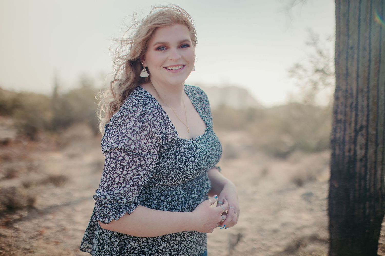 Desert photoshoot featuring a floral dress against a backdrop of cacti and warm sunlight.