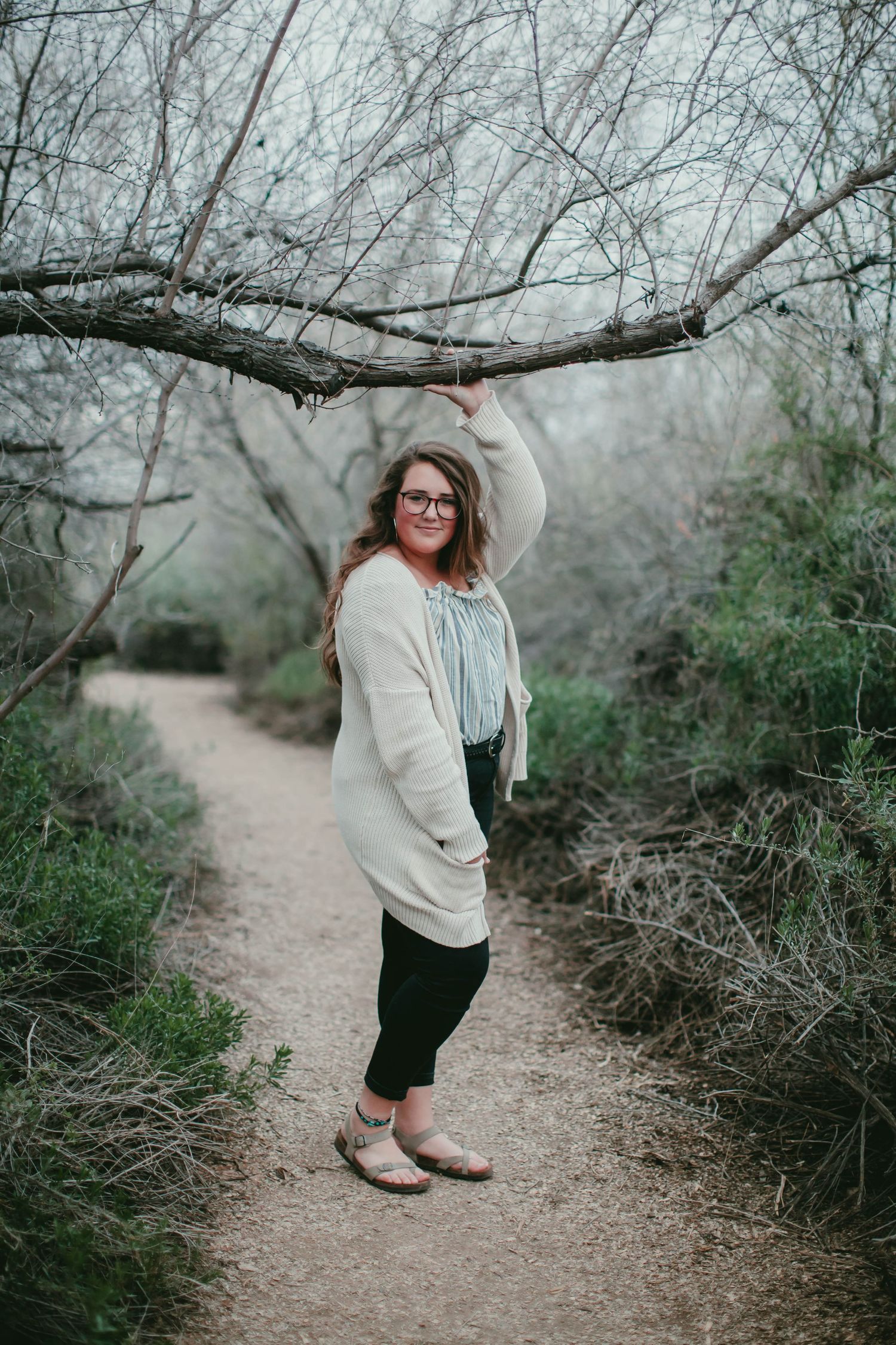 Playful pose under tree branches on a winding dirt path.
