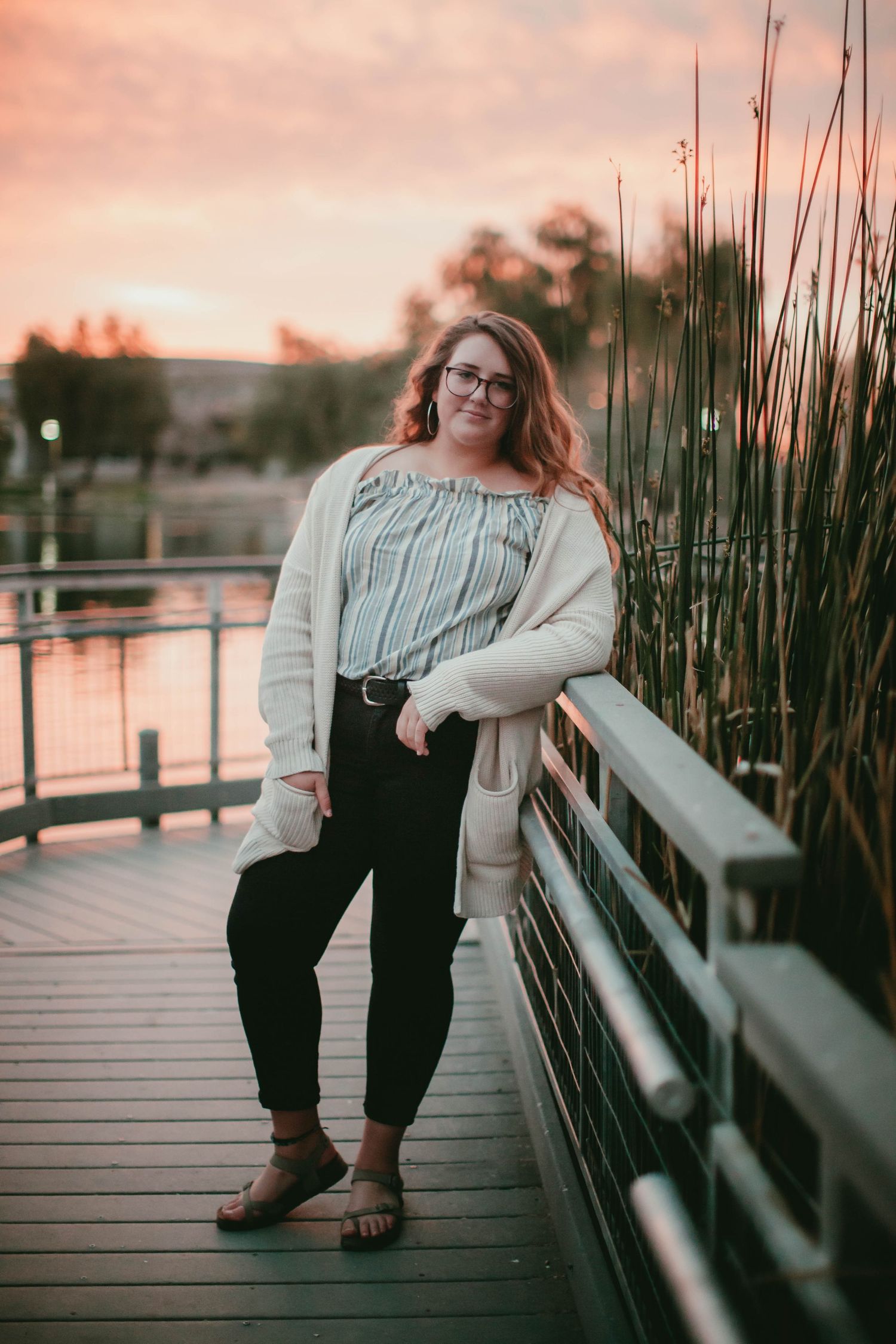 Sunset portrait on boardwalk with cozy cardigan and striped top.