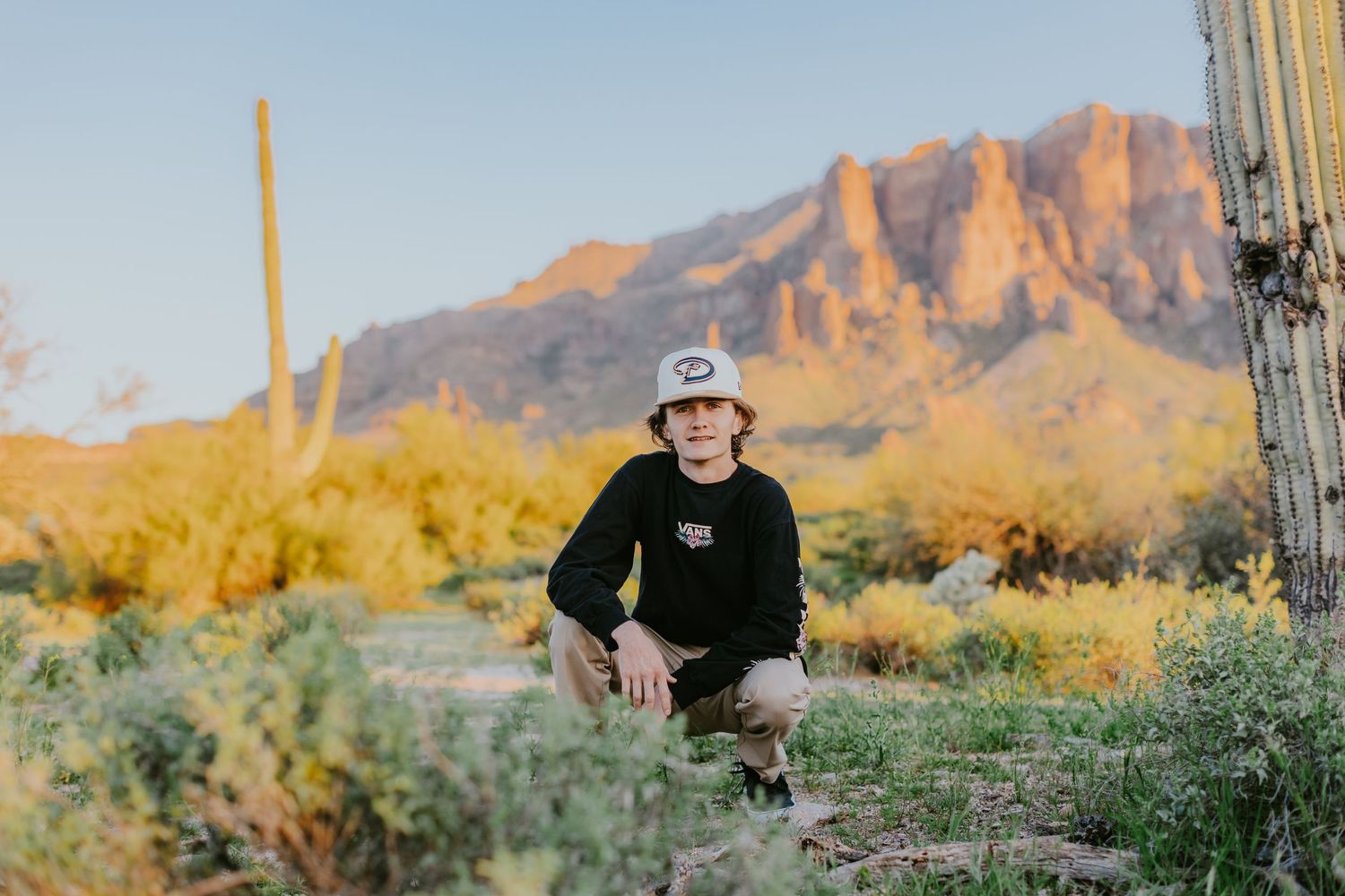 Casual portrait by saguaro cactus with golden Superstition Mountains in late afternoon light.