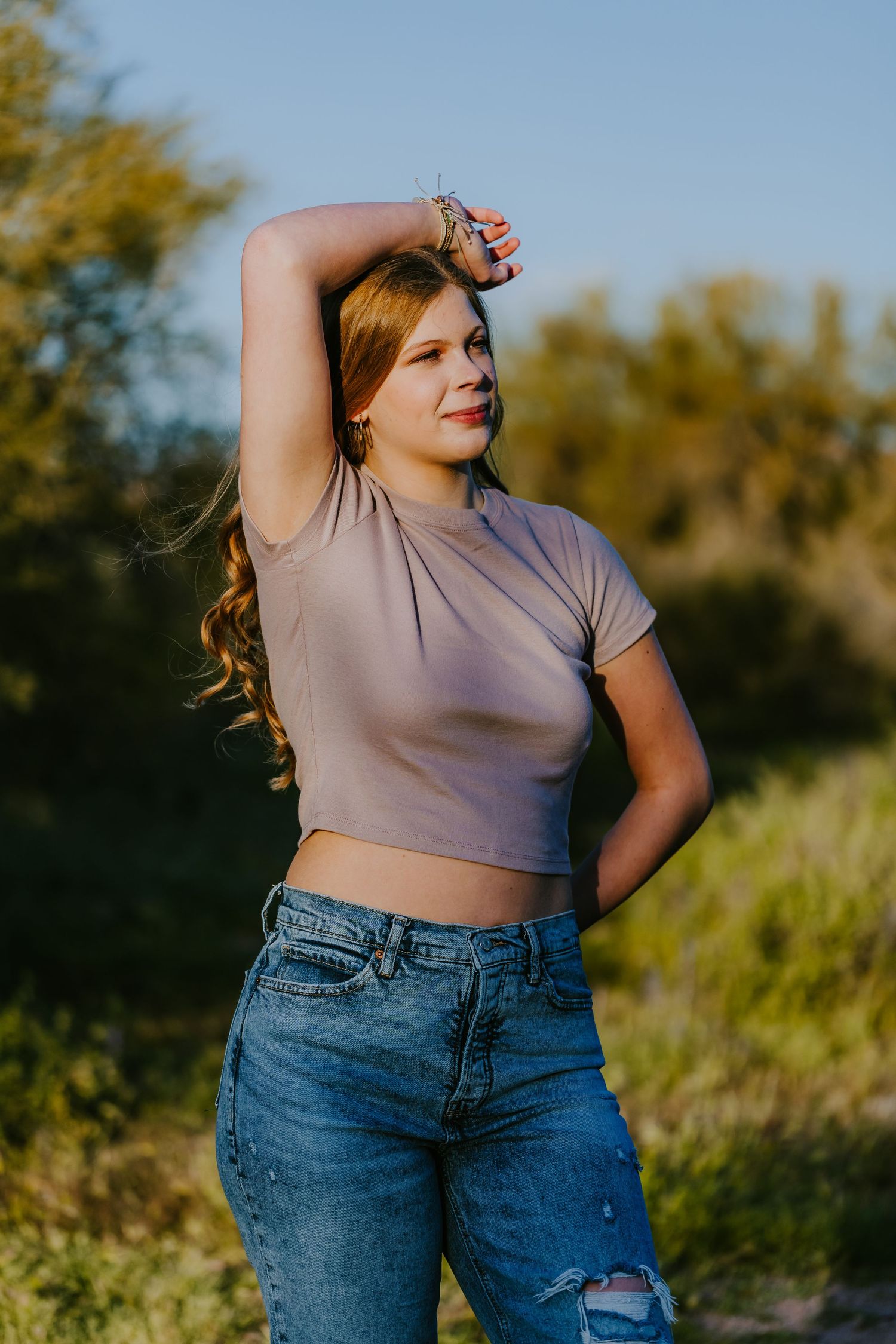 Desert photoshoot featuring casual attire with denim and crop top at sunset.