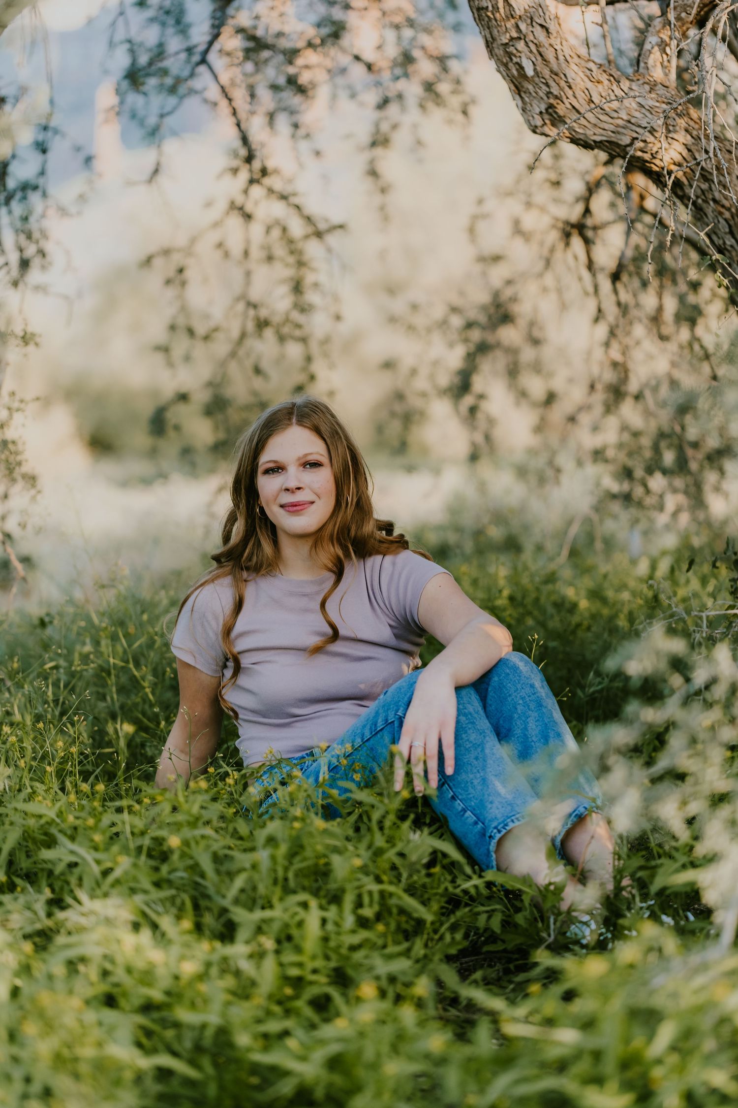Casual outdoor photoshoot among green foliage with warm evening light filtering through trees.