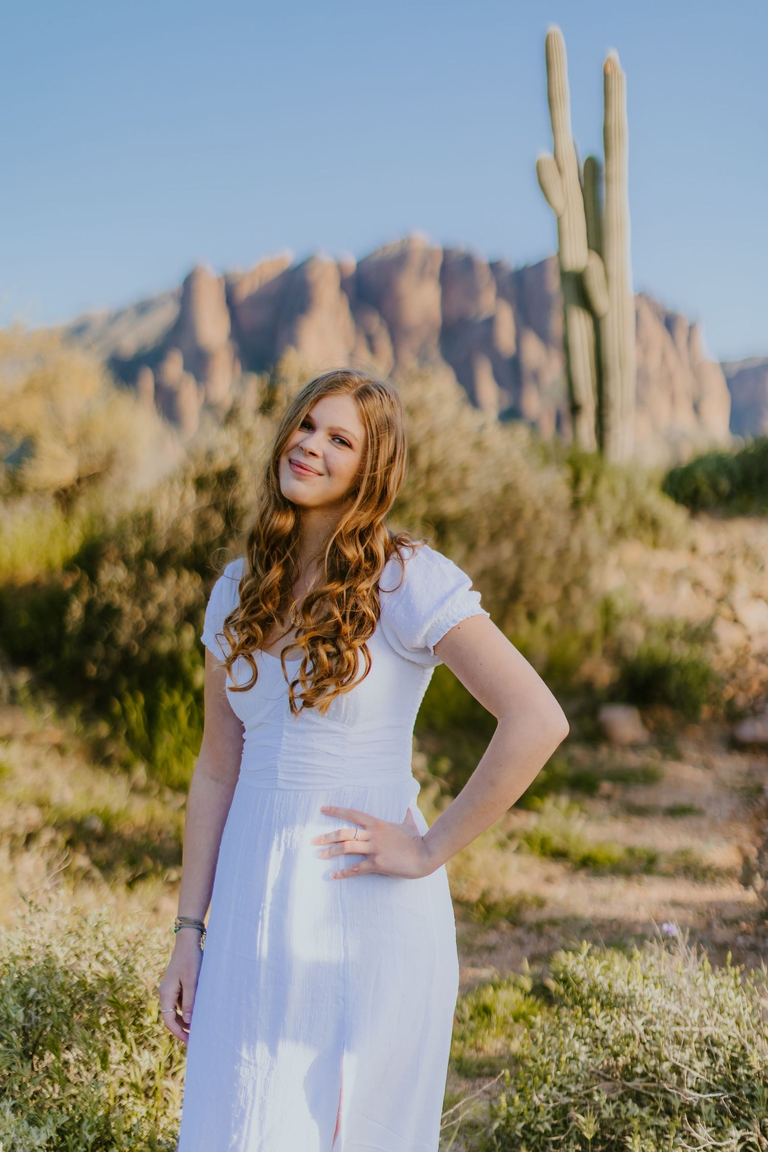 White dress portrait with Superstition Mountains and saguaro cactus in background.