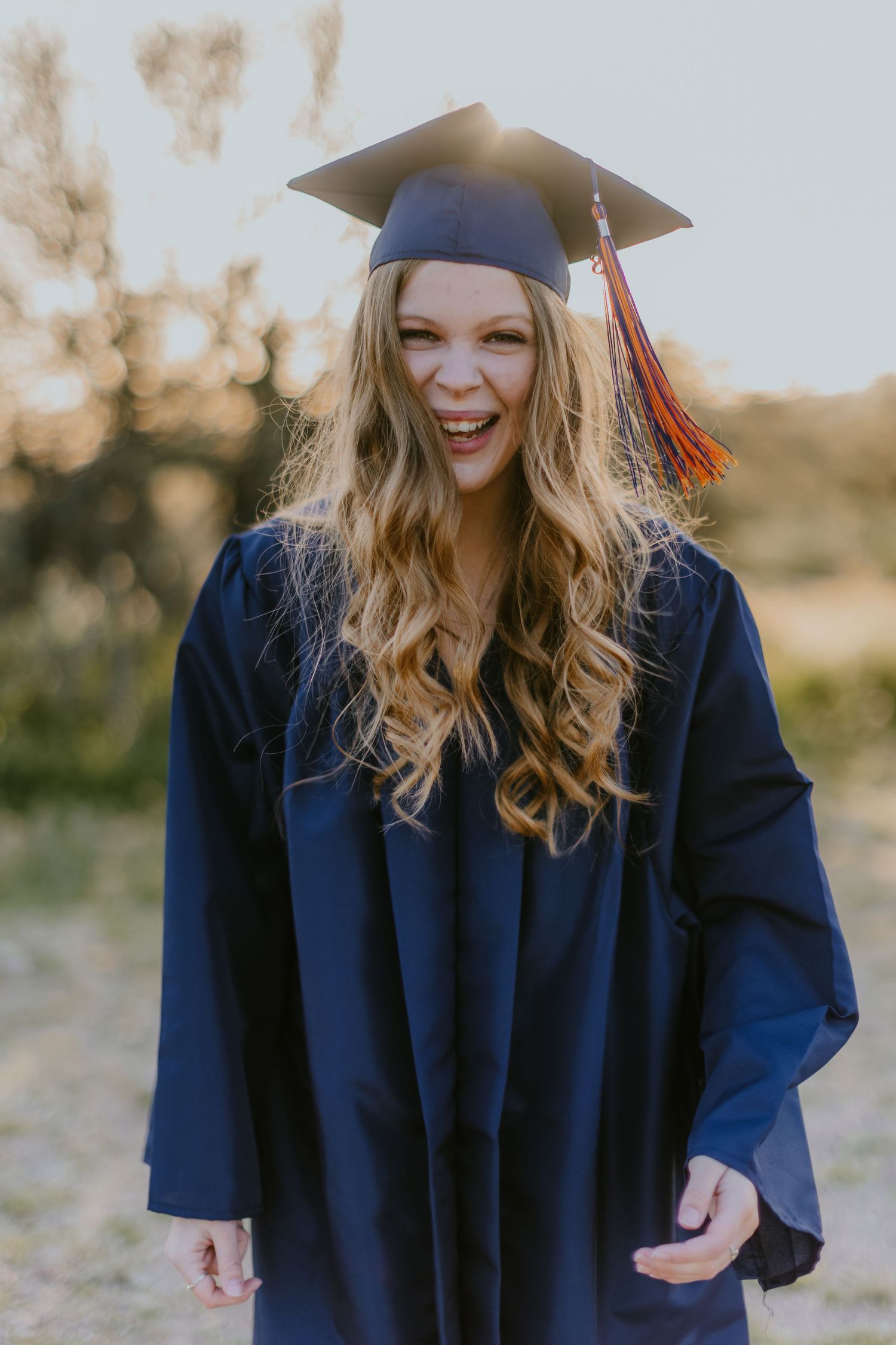 Joyful graduation portrait session with cap and gown in desert landscape.
