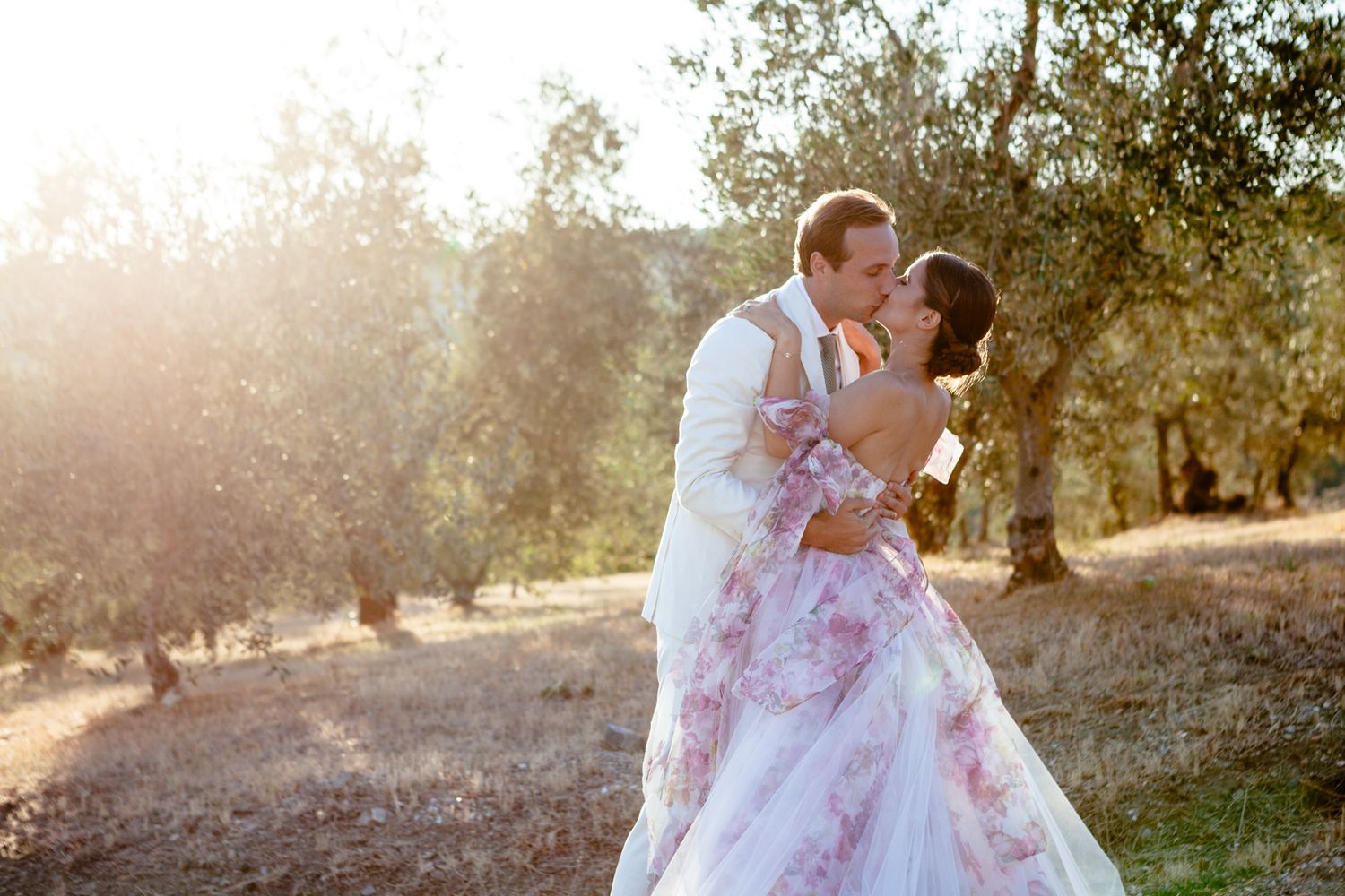 bride and groom kiss at sunset in an olive grove