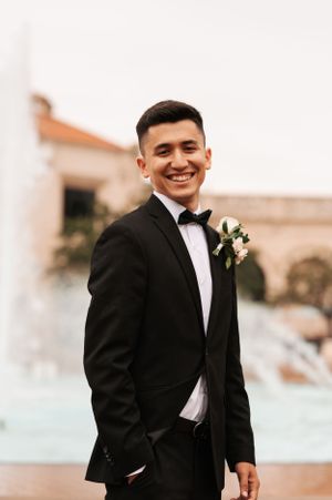 Candid moments of groom in black tuxedo during wedding day portraits.