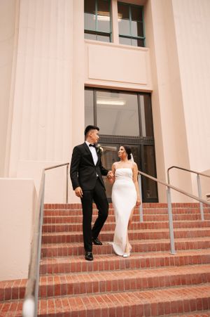 Romantic wedding portrait of couple in formal attire on brick steps at sunset.