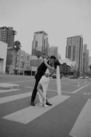 Black and white photo of couple in dramatic dip pose on urban crosswalk.