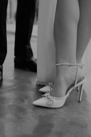 Close-up of elegant bridal shoes and groom's formal footwear on stone floor.