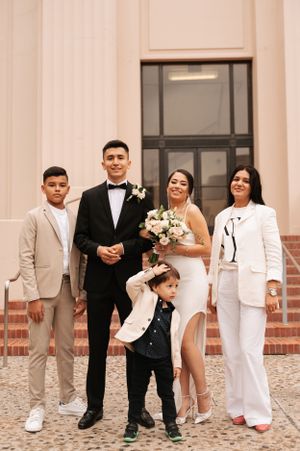 Wedding group photo of family members posing together on steps in formal attire.