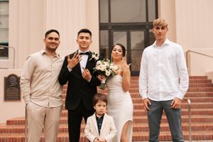 Wedding party poses on brick steps outside a building with traditional formal attire.