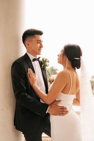 Romantic wedding moment captured between newlyweds against a classical pillar backdrop.