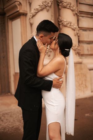 A tender wedding moment captured against an ornate architectural backdrop.