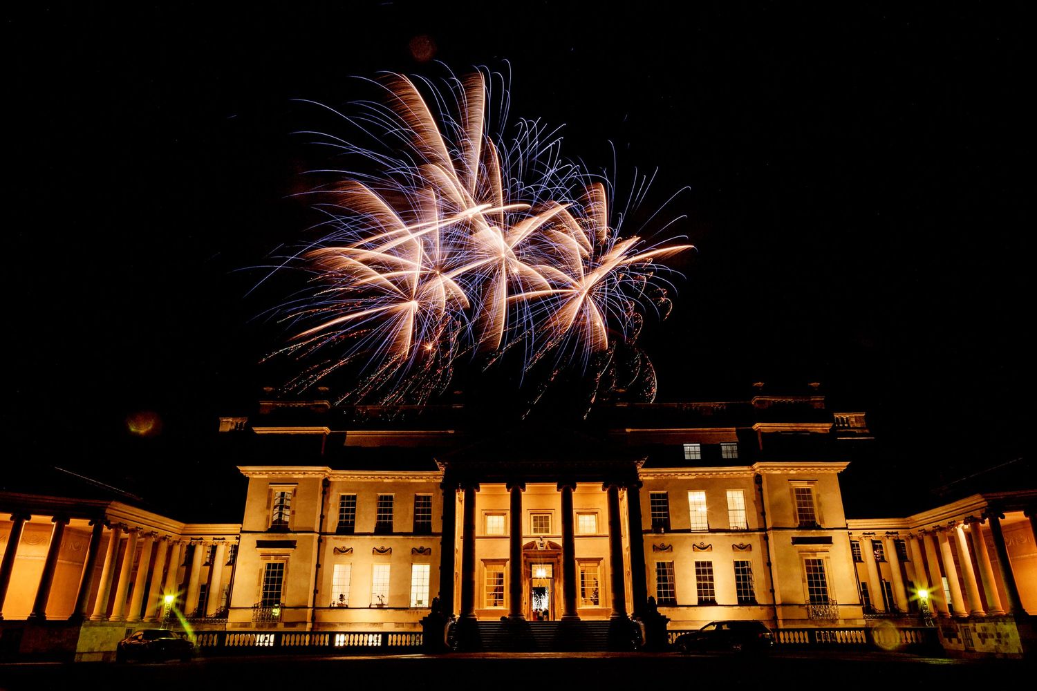 Fireworks explode over a grand historical building with classical architecture at night.