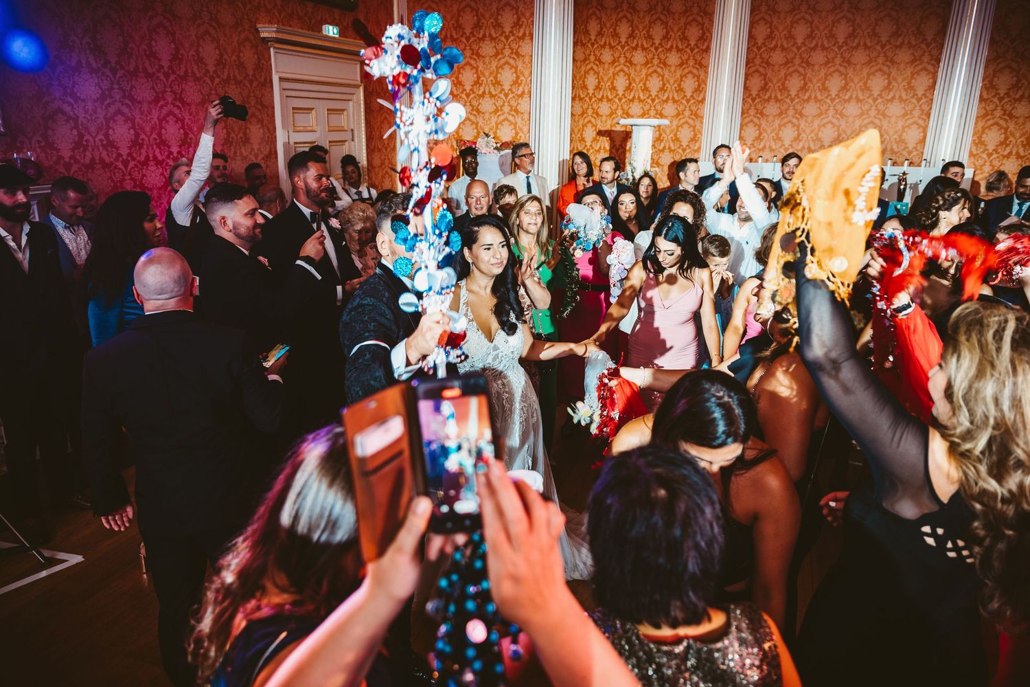 Energetic wedding party celebration with guests dancing under blue party lights.