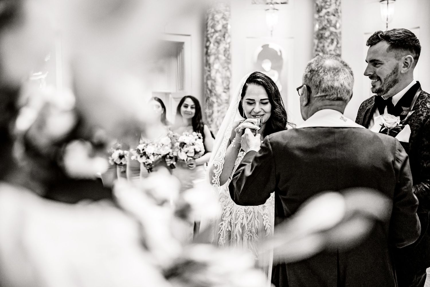 Black and white candid photograph of guests laughing during a wedding reception celebration.