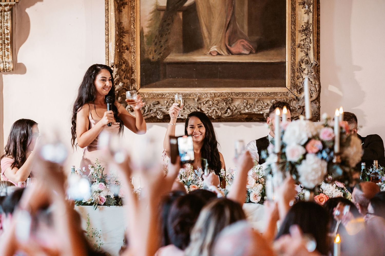 Wedding celebration at an elegant venue with guests raising glasses during toasts.