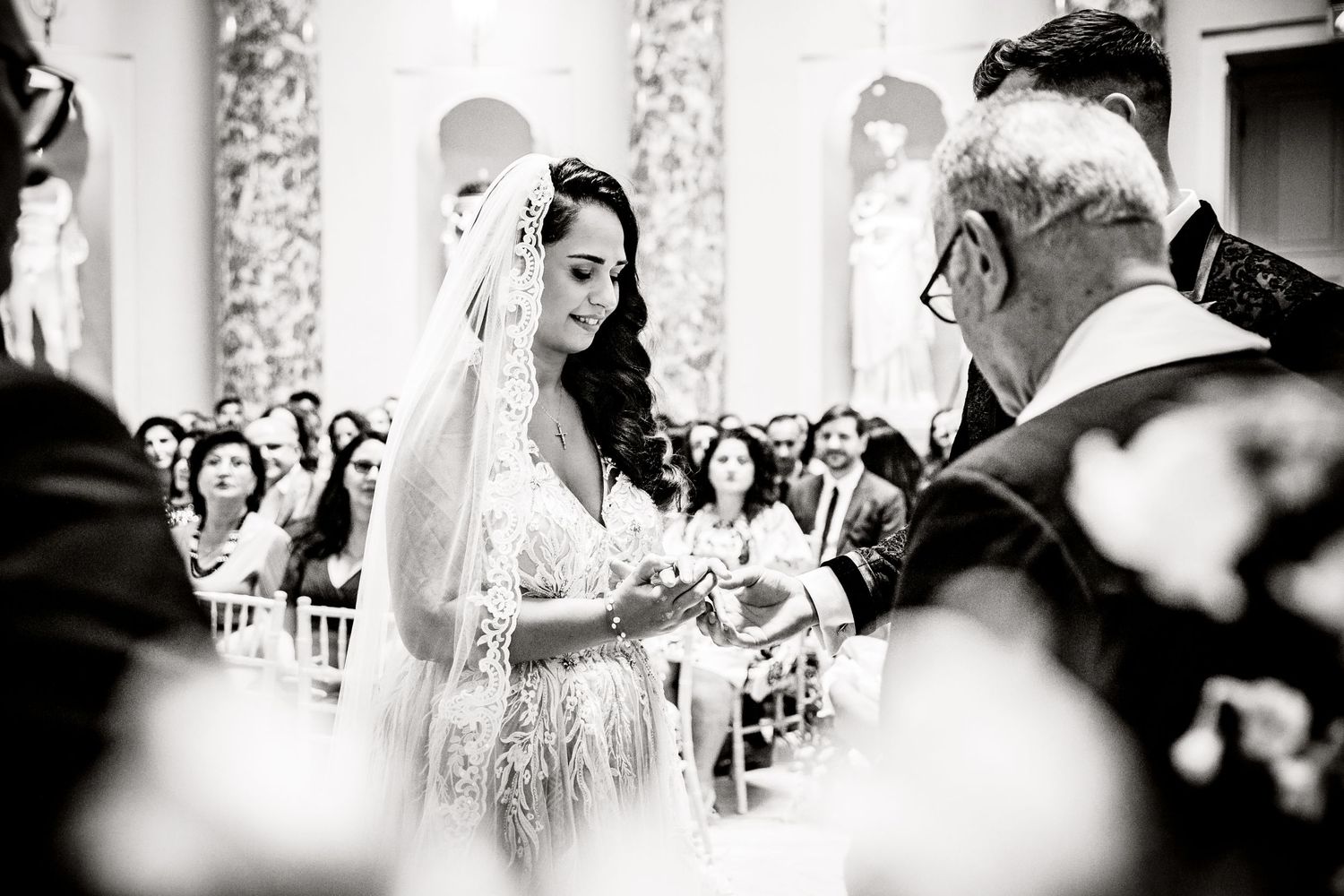 Black and white image of a wedding ceremony in an ornate church interior.