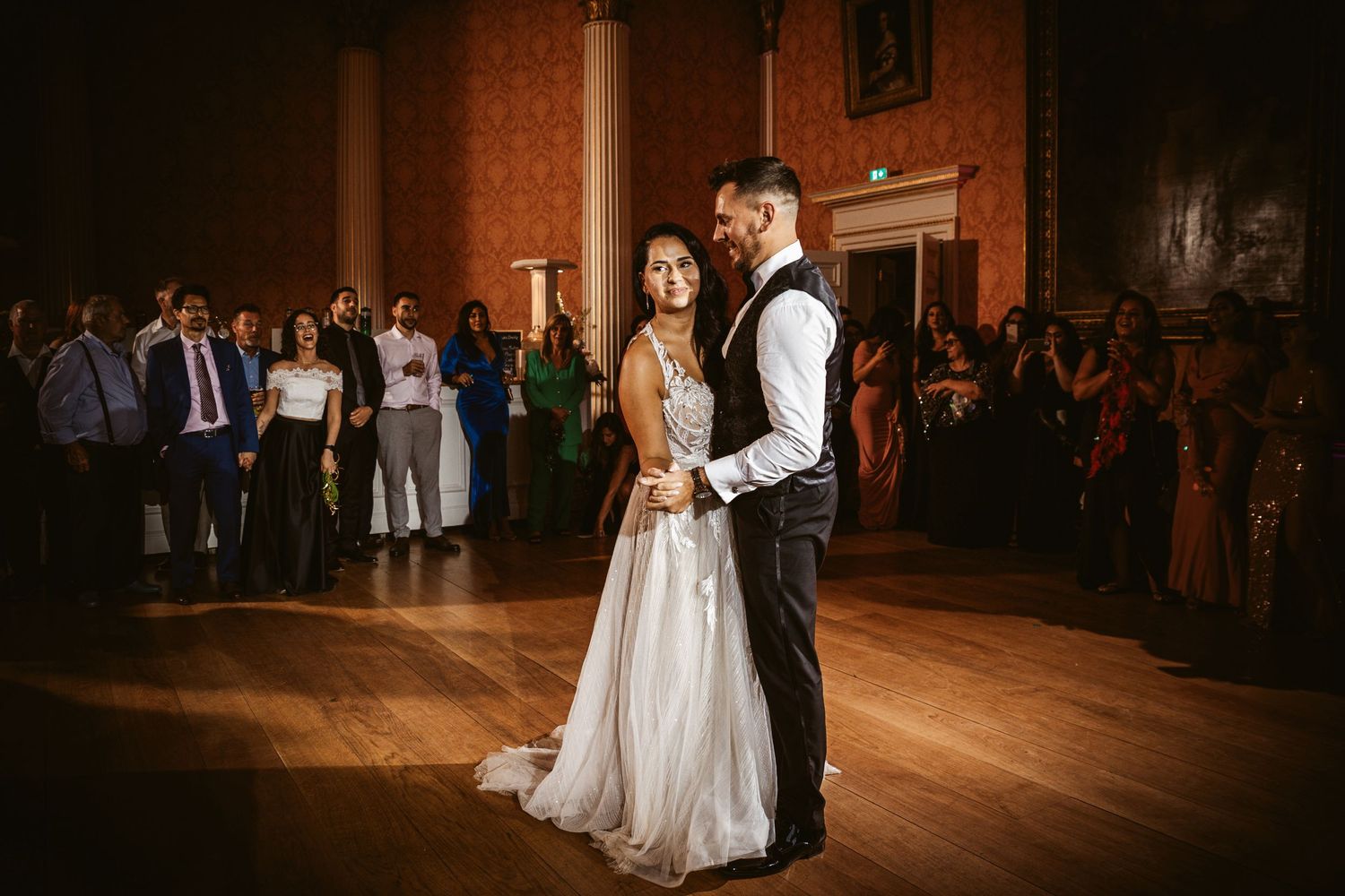 Wedding couple sharing intimate dance moment in elegant ballroom with warm lighting.