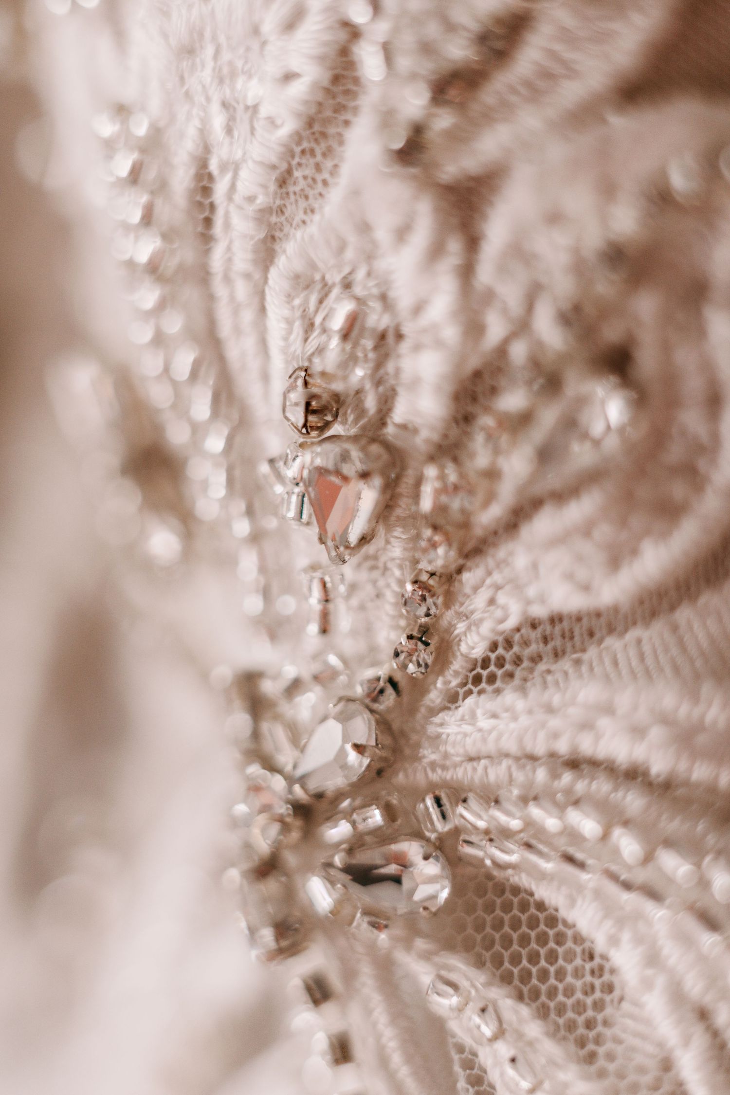 Macro detail of delicate beadwork and lace embellishments in soft sepia tones.
