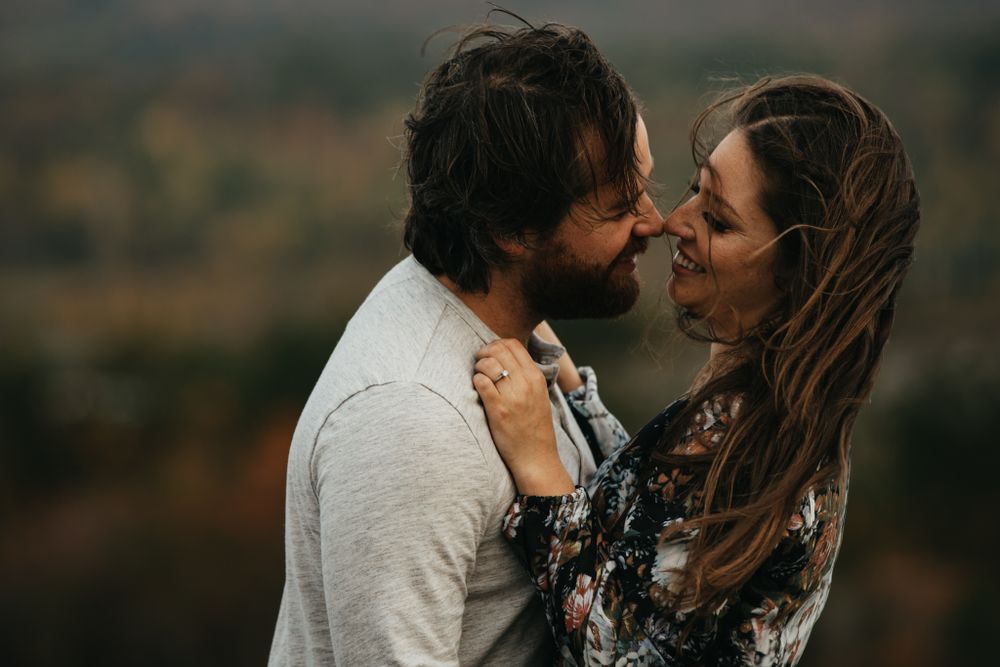Intimate outdoor portrait of couple embracing against autumn landscape.