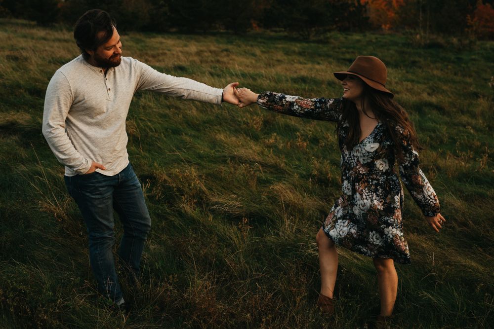 Couple embraces on a grassy hillside during golden hour sunset photoshoot.