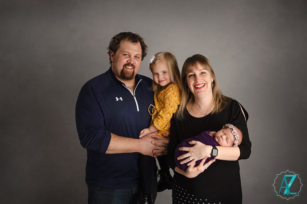 A family portrait with a navy and yellow color scheme against a grey studio backdrop.