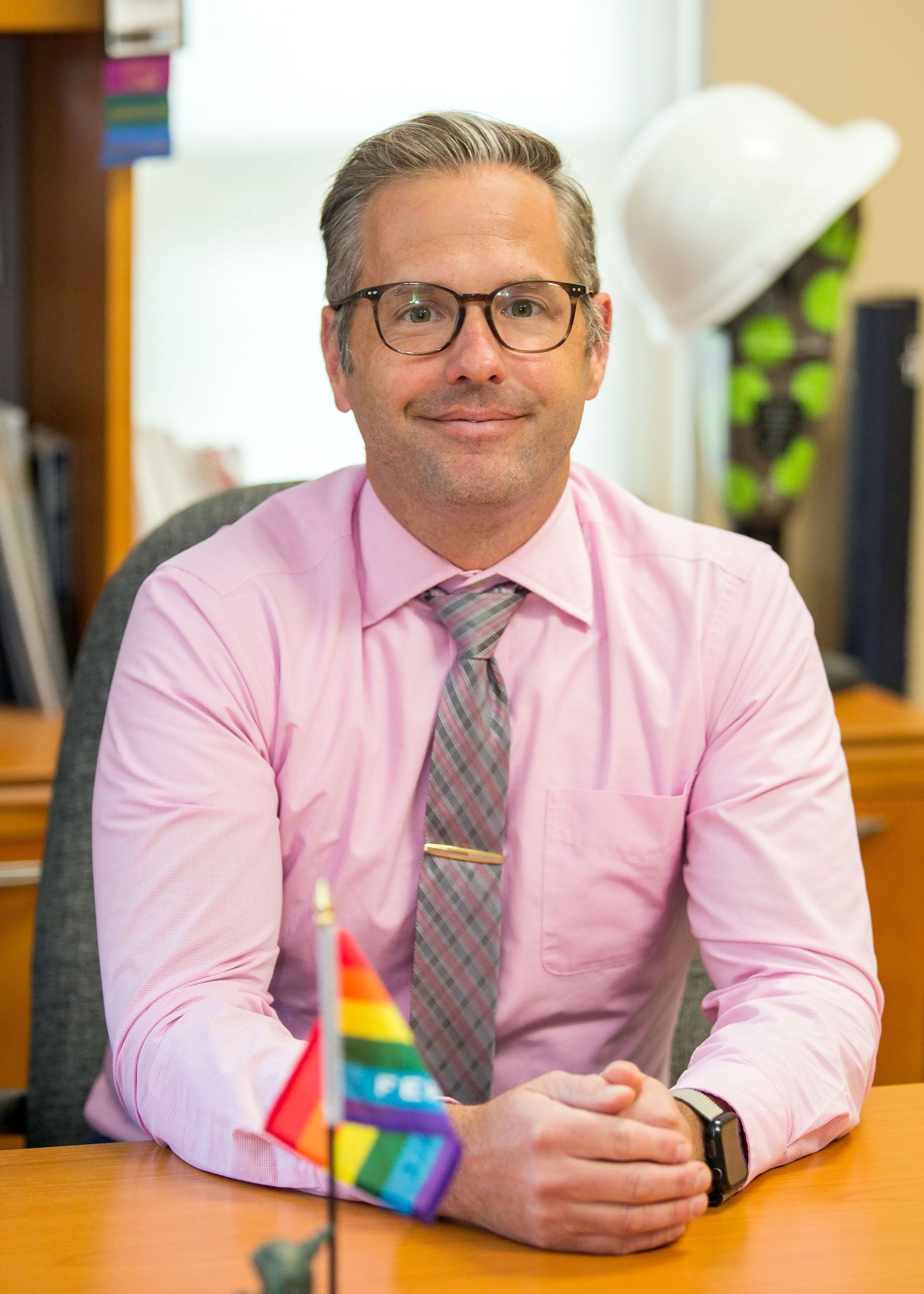 LGBTQ male sitting at desk with hands folded