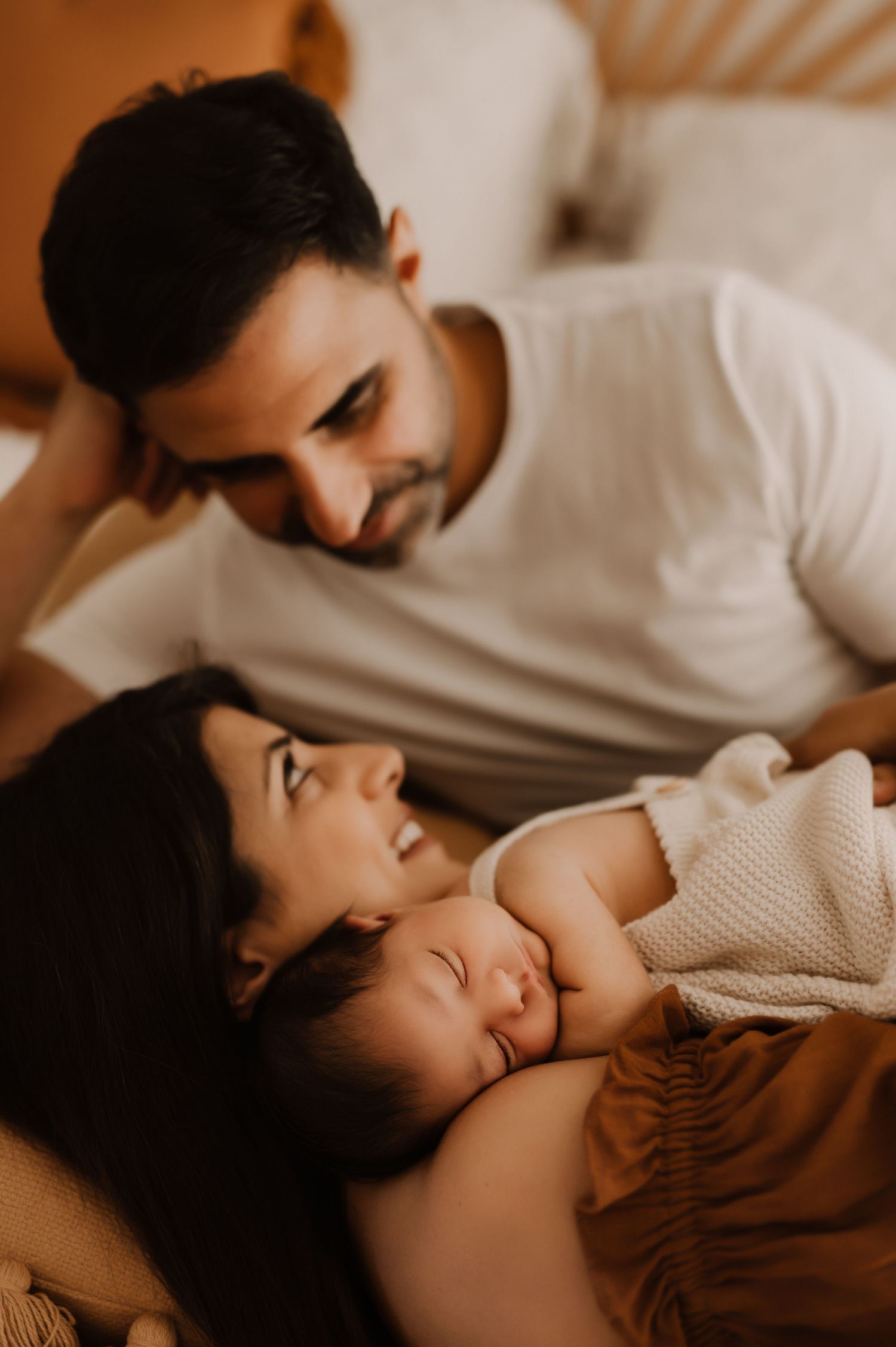 Intimate family moment as parents lovingly watch their sleeping baby.