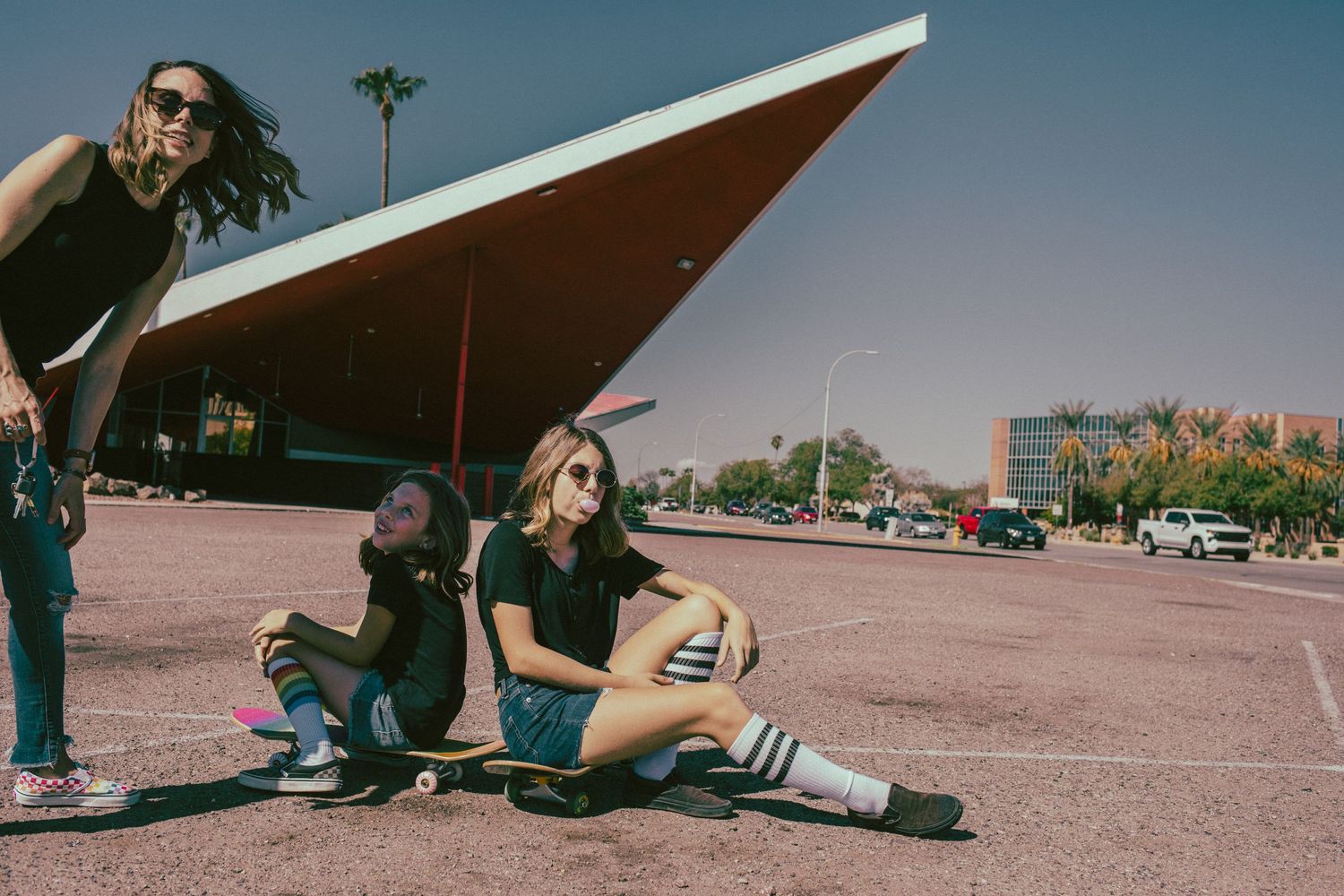 Mother and children ride skateboards in front of iconic bowling alley in Phoenix, AZ by Creative Family Photographer