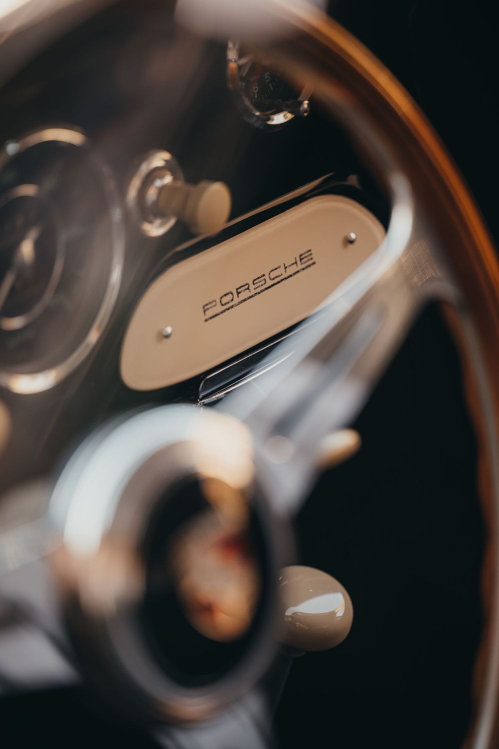 Macro shot of a Porsche steering wheel emblem with shallow depth of field.
