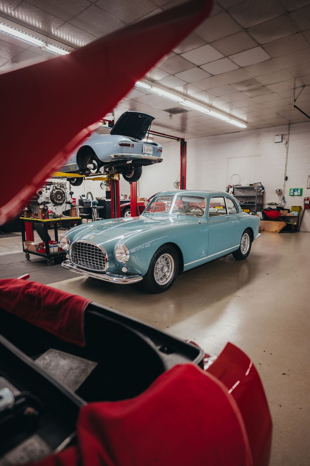 Classic light blue convertible sports cars displayed in underground garage.