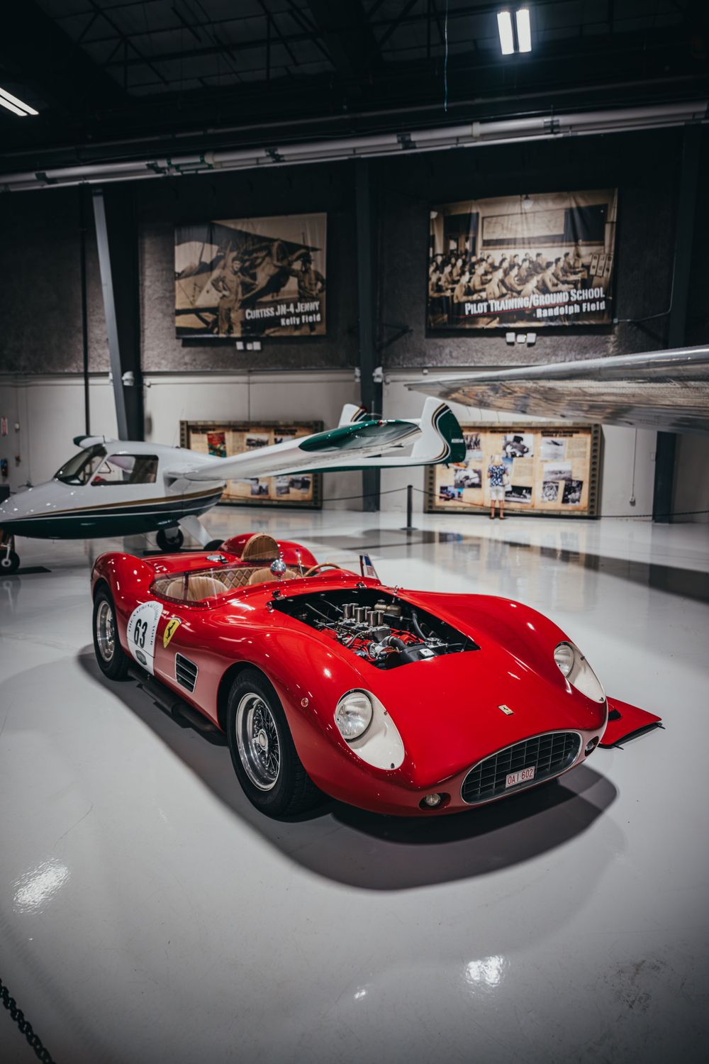 Sleek red vintage Ferrari race car displayed in a pristine museum showroom.