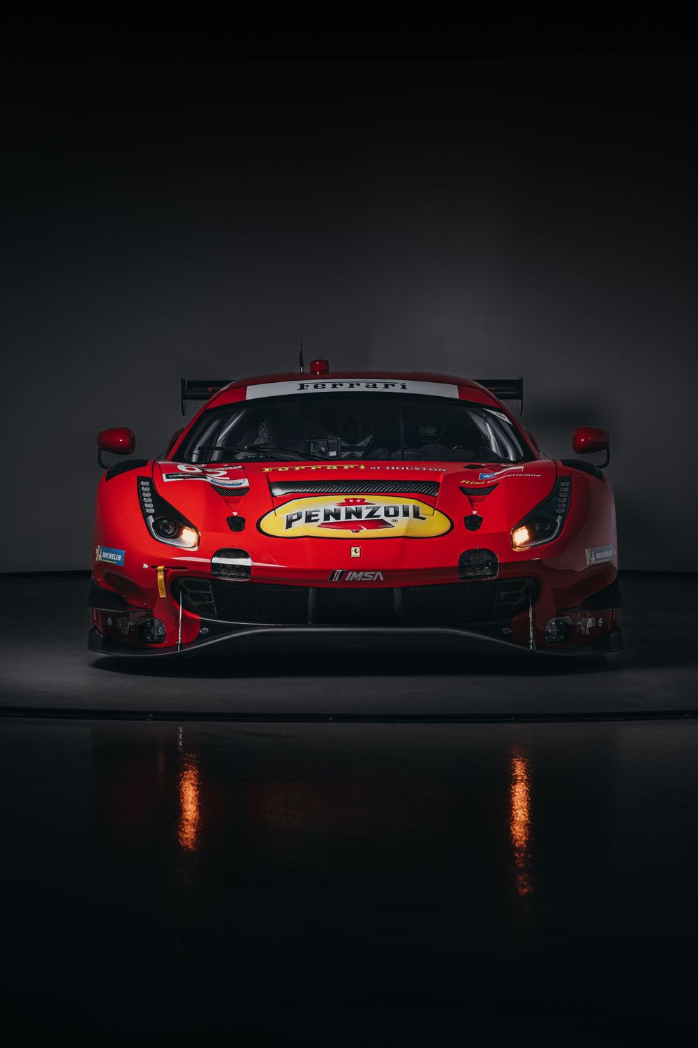 Red Ferrari race car shown in dramatic side profile with glowing lights.
